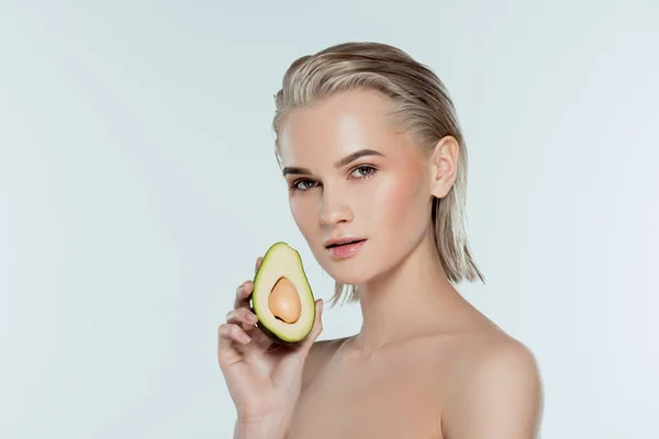 Красивая молодая женщина, позирующая с авокадо, изолированная на сером — стоковое фото