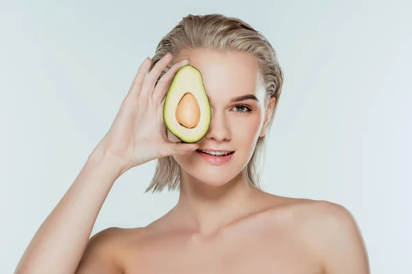 Lächelndes blondes Mädchen posiert mit Avocado, isoliert auf grau — Stockfoto