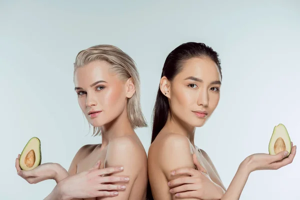 Attractive girls posing with two halves of avocado, isolated on grey, skin care concept — Stock Photo