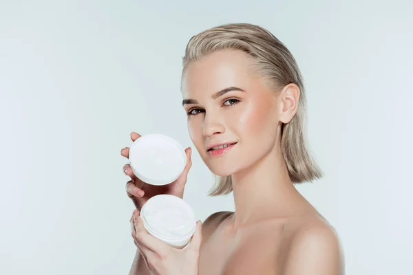 Nude woman holding face cream in plastic container, isolated on grey — Stock Photo