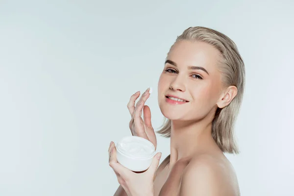 Happly woman applying face cream, isolated on grey — Stock Photo