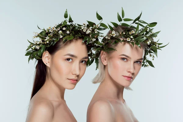 Hermosas chicas multiétnicas en coronas florales verdes, aisladas en gris - foto de stock