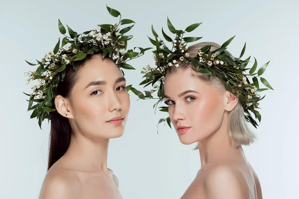 Naked multiethnic girls in floral wreaths, isolated on grey — Stock Photo