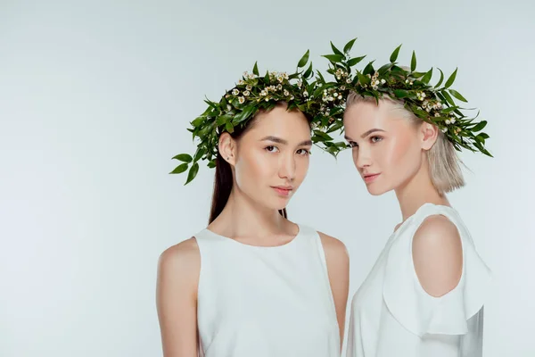 Multicultural women posing in floral wreaths, isolated on grey — Stock Photo