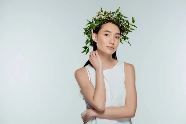 Hermosa chica asiática posando en corona floral, aislado en gris - foto de stock