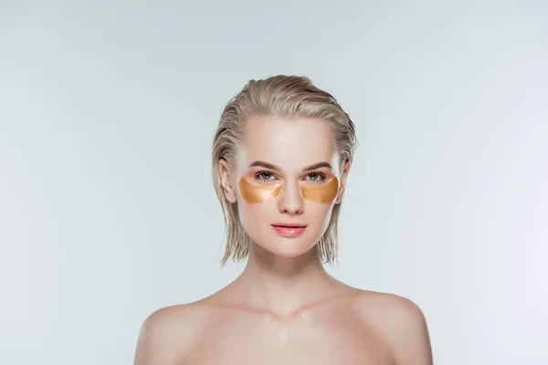 Nude woman with golden eye patches, isolated on grey — Stock Photo