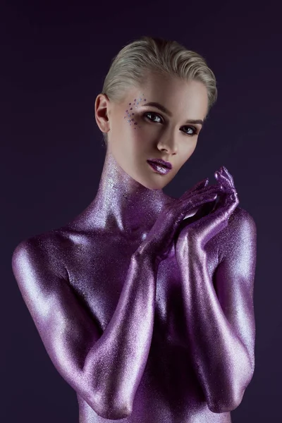 Schöne modische Mädchen posiert in ultraviolettem Glitzer, isoliert auf lila — Stockfoto