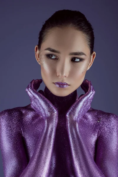 Stylische attraktive asiatische Mädchen in ultraviolettem Glitzer, isoliert auf lila — Stockfoto