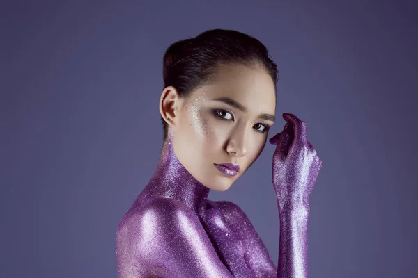 Fashionable attractive asian girl in ultra violet glitter, isolated on purple — Stock Photo