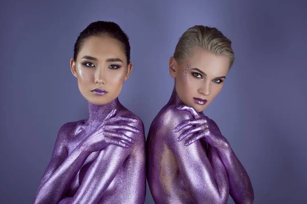 Multiethnic trendy girls in purple glitter, isolated on violet — Stock Photo