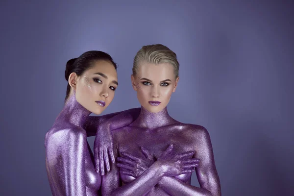 Модные мультикультурные девушки в фиолетовых блестках, изолированные на фиолетовых — стоковое фото