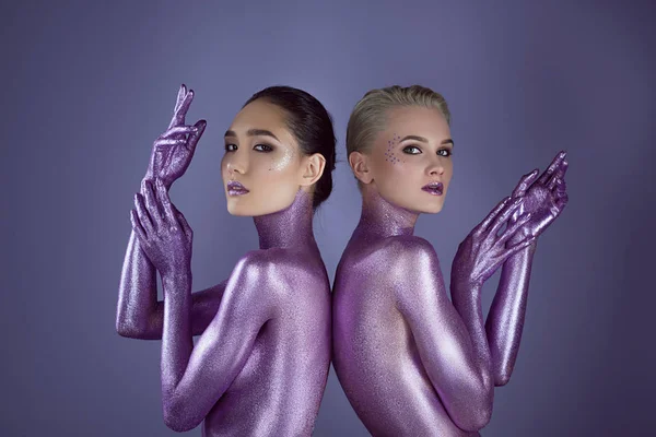 Séduisantes filles nues multiethniques aux paillettes ultra violettes, isolées sur violet — Photo de stock