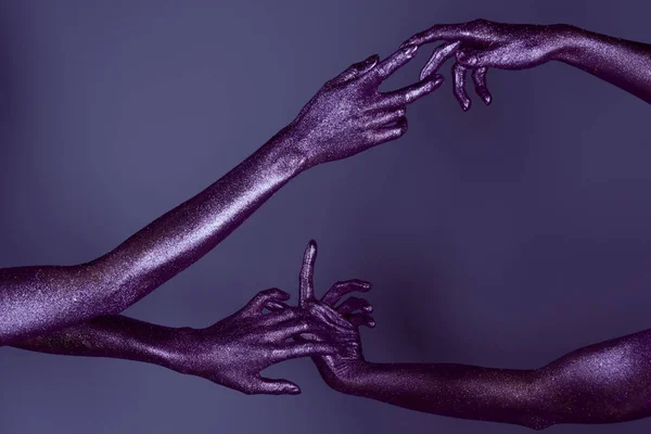 Обрезанный вид нежных женских рук в фиолетовых блестках, касающихся друг друга — стоковое фото