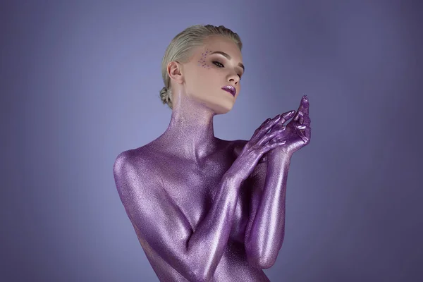 Нежная стильная девушка, окрашенная ультрафиолетовым блеском, изолированная на фиолетовый — стоковое фото