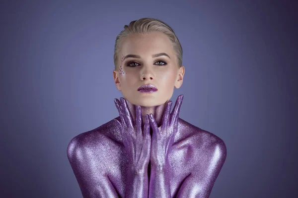 Attractive fashionable woman painted with purple glitter, isolated on violet — Stock Photo
