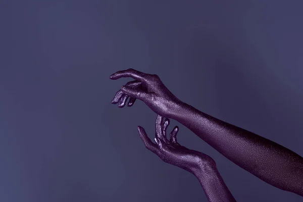 Cropped view of hands painted in violet glitter, isolated on purple — Stock Photo