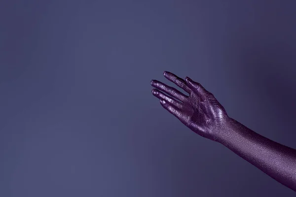 Partial view of tender hand in ultra violet glitter, isolated on purple — Stock Photo