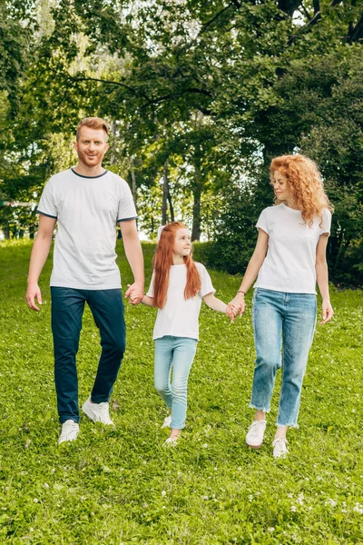 Счастливая семья с одним ребенком, держащимся за руки и гуляющим вместе в парке — стоковое фото