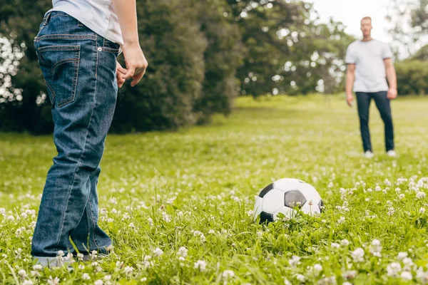 Обрезанный снимок отца и сына, играющих с футбольным мячом в парке — стоковое фото