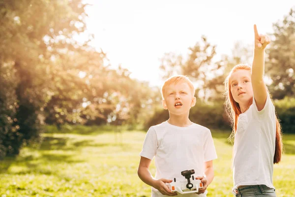 Cute kids playing with drone and looking up at park — Stock Photo