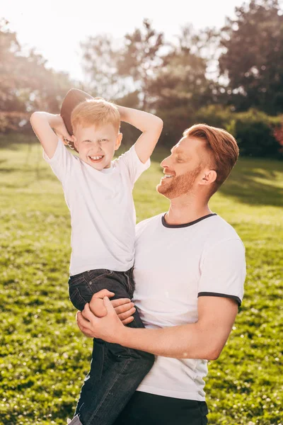 Feliz padre e hijo jugando con pelota de rugby en el parque - foto de stock