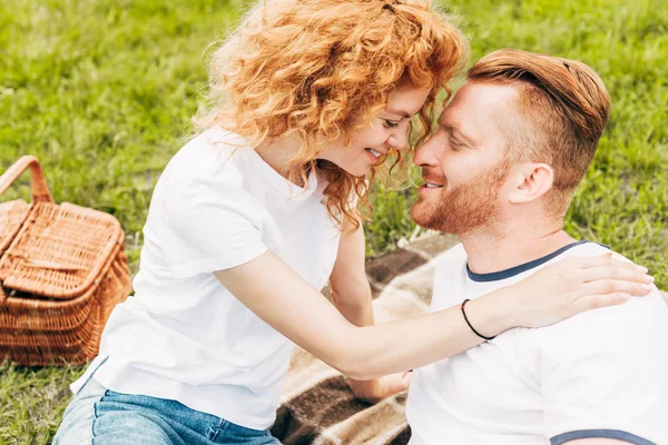Боковой вид счастливой рыжей пары, улыбающейся вместе на пикнике в парке — стоковое фото