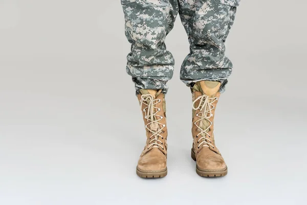 Tiro recortado de soldado en uniforme militar y botas aisladas en gris - foto de stock