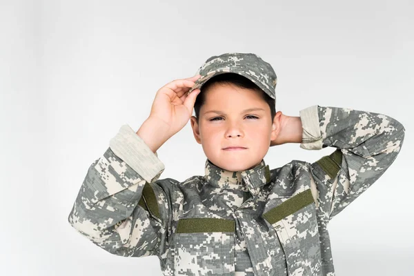 Retrato de niño pequeño en uniforme militar posando sobre fondo gris - foto de stock