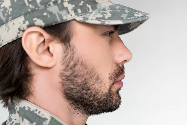 Vista lateral de soldado barbudo confiado en uniforme militar mirando hacia otro lado aislado en gris - foto de stock