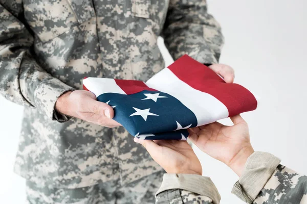 Tiro cortado de soldado dando dobrado bandeira americana para criança em roupas de camuflagem no fundo cinza — Fotografia de Stock