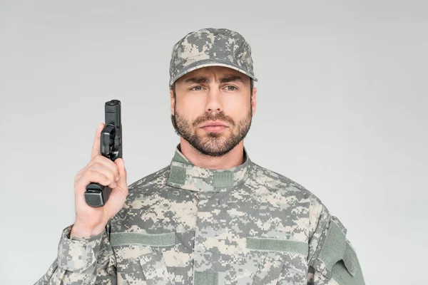 Портрет солдата-чоловіка у військовій формі, який тримає пістолет ізольовано на сірому — стокове фото