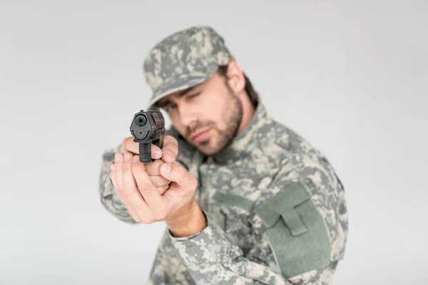 Foco seletivo de soldado masculino em uniforme militar segurando arma isolada em cinza — Fotografia de Stock