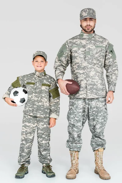 Family in military uniforms holding soccer and rugby balls on grey background — Stock Photo