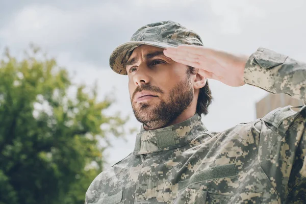 Portrait of confident soldier in military uniform with cloudy sky on background — Stock Photo