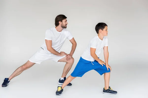 Father and son in white shirts stretching on grey backdrop — Stock Photo