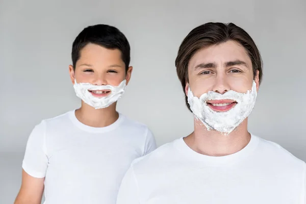 Portrait de père et fils souriants avec mousse à raser sur les visages isolés sur gris — Photo de stock