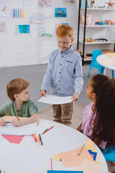 Entzückende multikulturelle Kinder mit Papieren im Klassenzimmer — Stockfoto