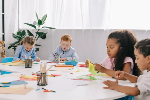 Multicultural preschoolers drawing pictures with pencils in classroom — Stock Photo