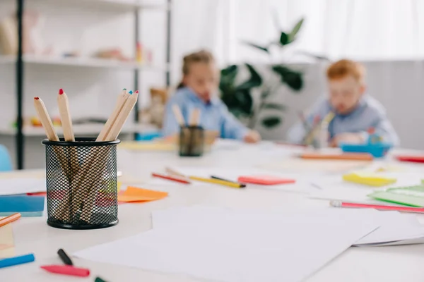 Enfoque selectivo de adorables niños dibujando imágenes en la mesa en el aula - foto de stock