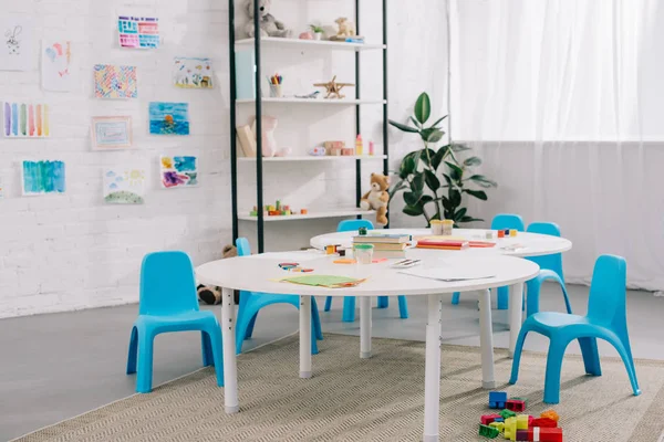 Nahaufnahme Spielzeug, bunte Ziegel auf dem Boden und Zeichnungen an der weißen Wand im leeren Klassenzimmer — Stockfoto