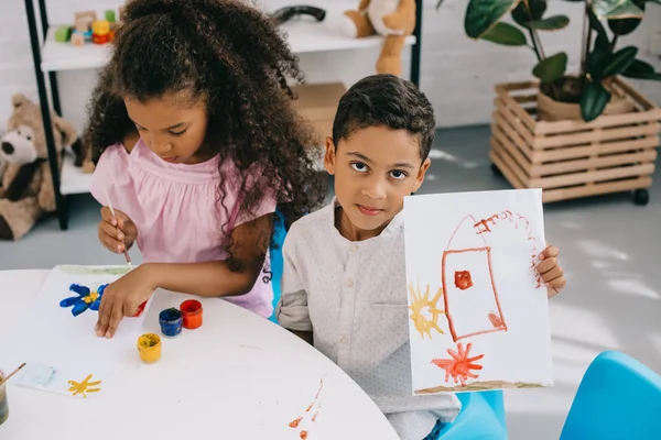 Hochwinkelaufnahme eines afrikanisch-amerikanischen Jungen, der Bild zeigt, während er in der Nähe eines Klassenkameraden im Klassenzimmer sitzt — Stockfoto