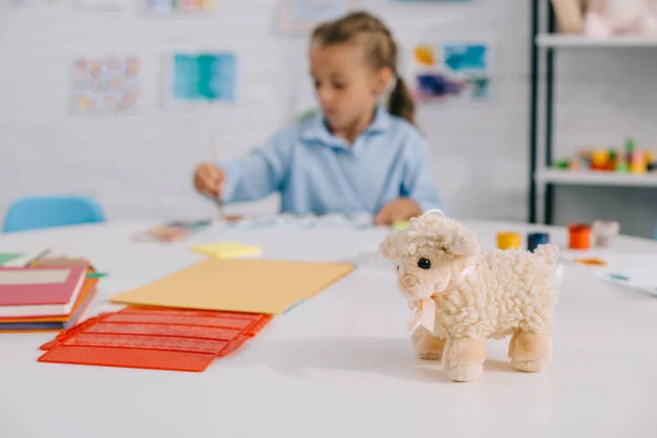 Foco seletivo de brinquedo ovelhas e criança desenho quadro na mesa no quarto — Fotografia de Stock