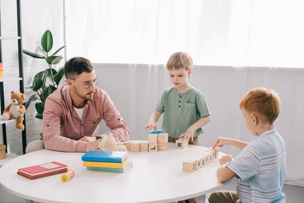 Preschoolers playing wit h wooden block with teacher near by in classroom — Stock Photo