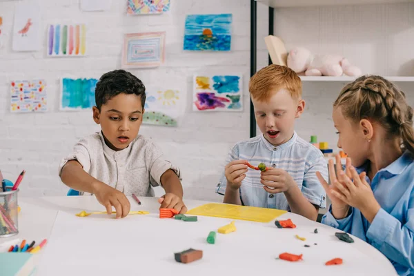 Porträt von niedlichen multiethnischen Vorschulkindern, die Figuren mit Knetmasse im Klassenzimmer formen — Stock Photo