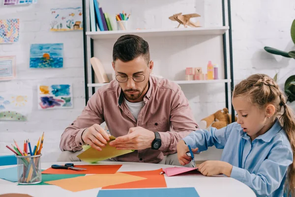 Portrait de l'enseignant et mignon papier de coupe préscolaire avec ciseaux att capable dans la salle de classe — Photo de stock