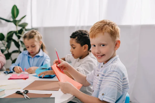 Adorable multicultural kids making paper applique in classroom — Stock Photo