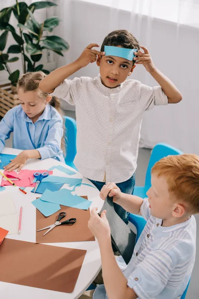 Adorables niños multirraciales haciendo apliques de papel en el aula — Stock Photo