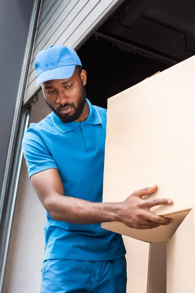 Vue à faible angle de l'homme de livraison afro-américain tenant la boîte — Photo de stock