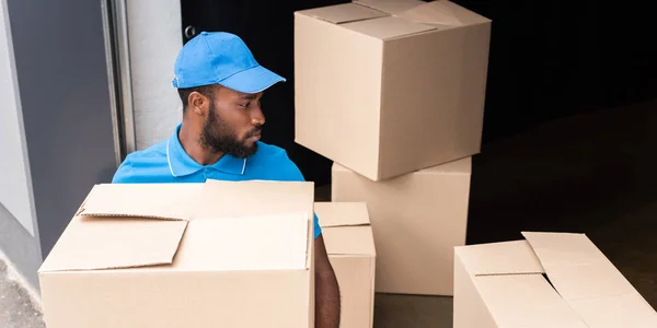 Africano americano entrega hombre holding caja cerca de almacenamiento - foto de stock