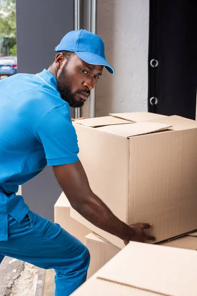 Africano americano repartidor hombre poner cajas en pila - foto de stock